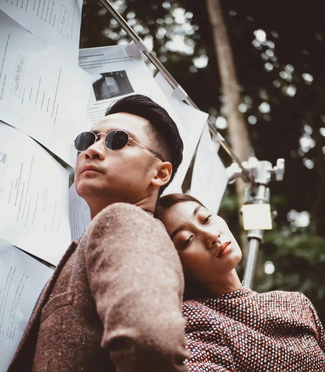 A man and woman posing back-to-back against paper documents.