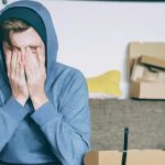 A stressed man covering his face with his hands.