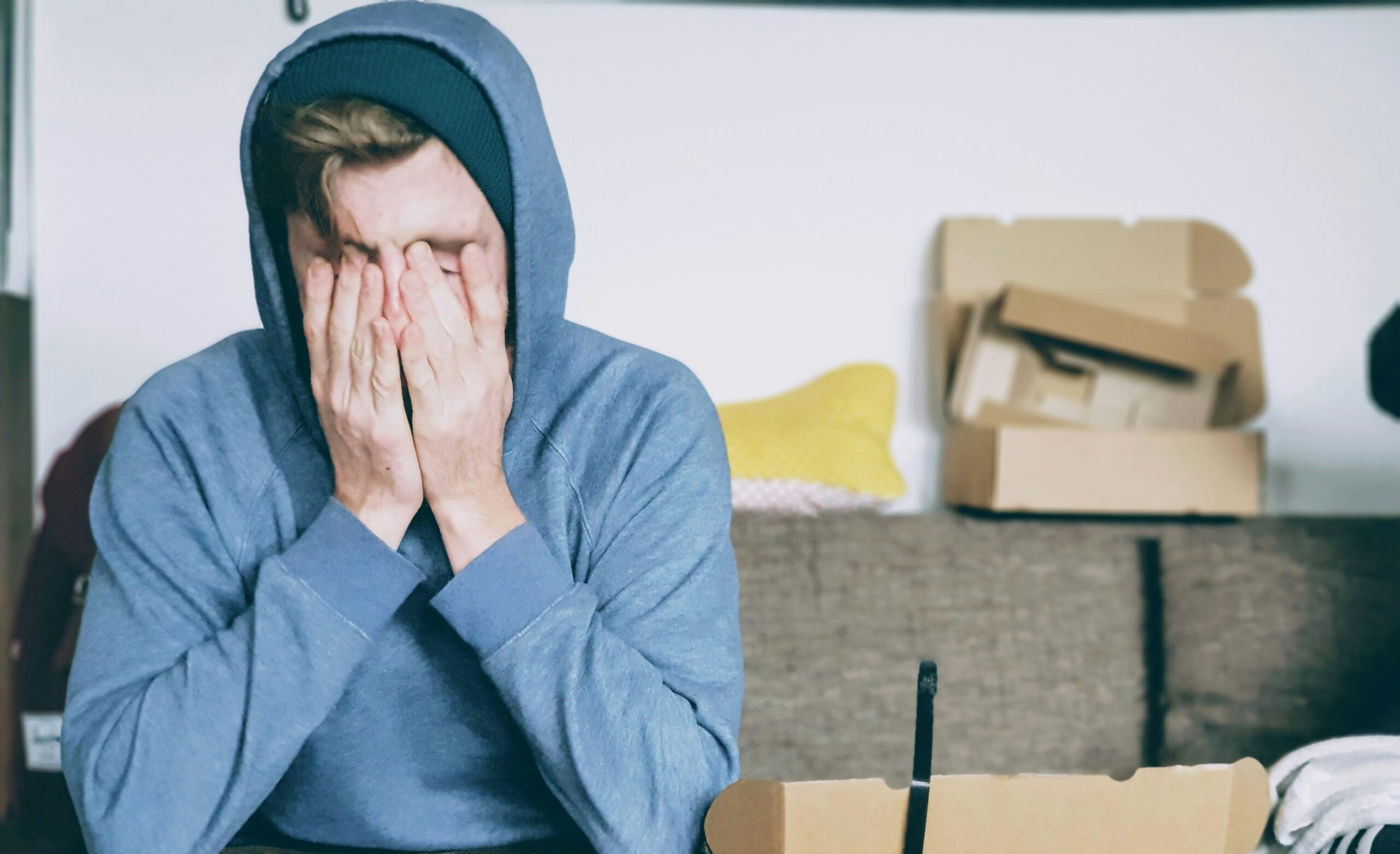 A stressed man covering his face with his hands.